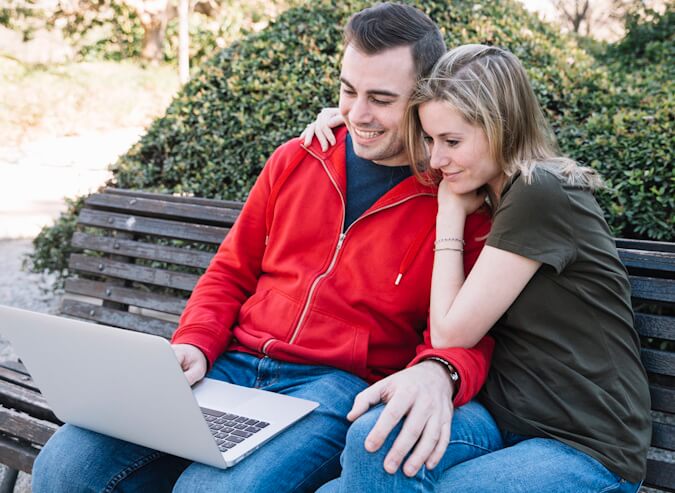 Fast, Fair Internet Across Alberta - couple sitting on bench with laptop connected to NetJOI Internet