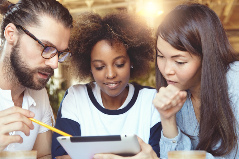 3 Adults sitting together on a sofa reviewing their options for an Internet Provider.