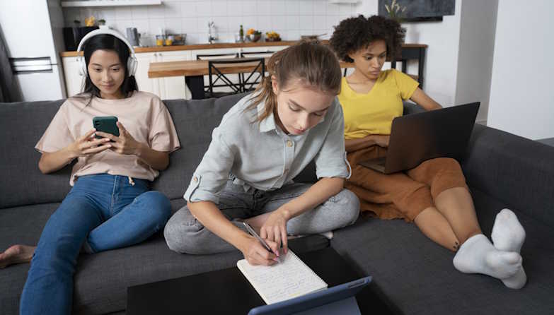 3 Ladies sitting on a couch each with their own electronic device using NetJOI Unlimited Internet for work + fun.